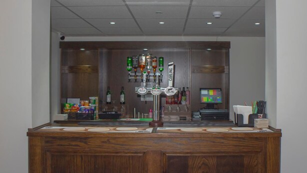 A bar area with multiple liquor bottles, a cash register, and a computer monitor. - Primelodge Doncaster (Doncaster)