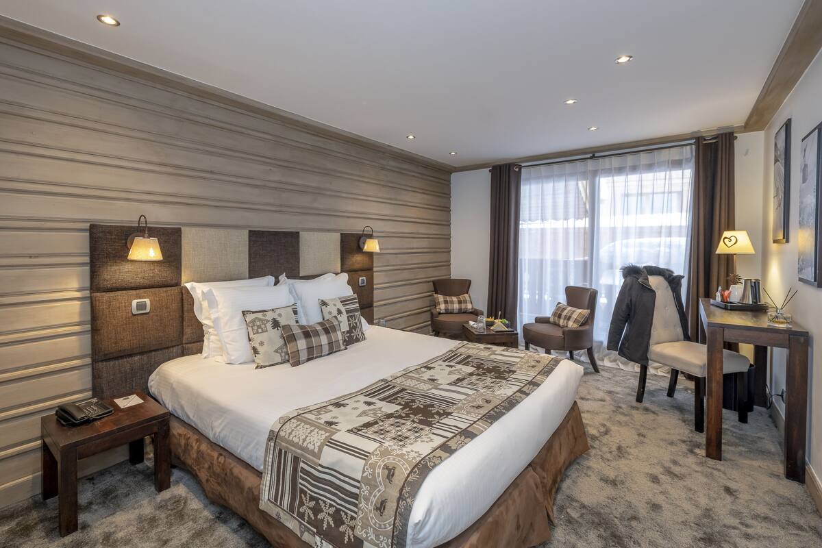 A hotel room with a large bed, two bedside tables, a desk, and a chair.