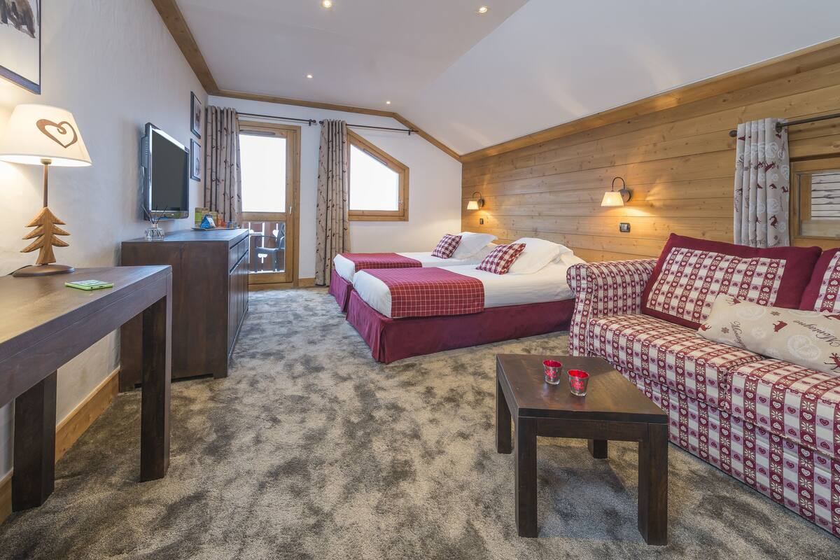 A cozy room with a bed, a sofa, a desk, and a TV.