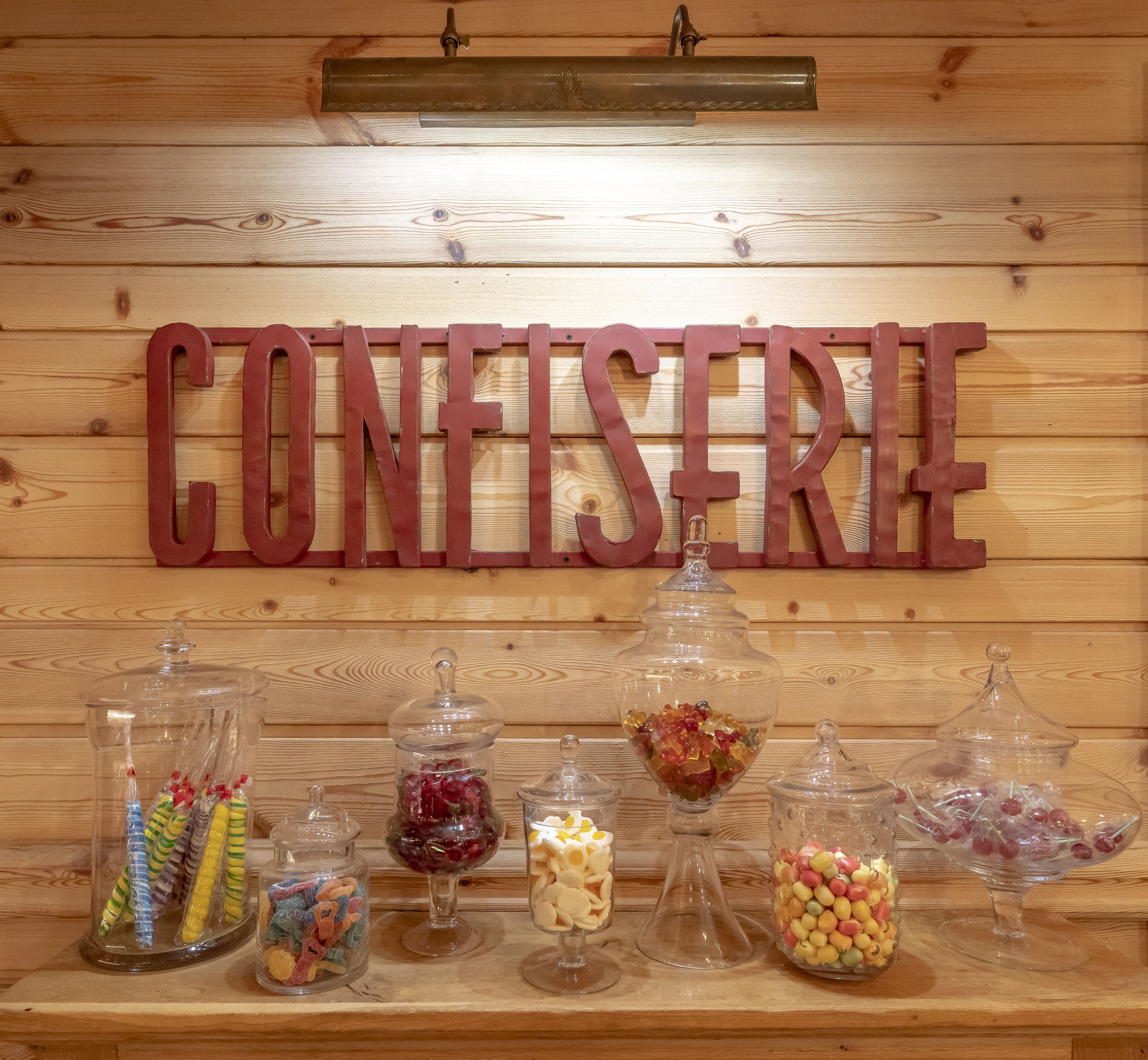 A wooden wall with the word "CONFISERIE" and various candy jars.