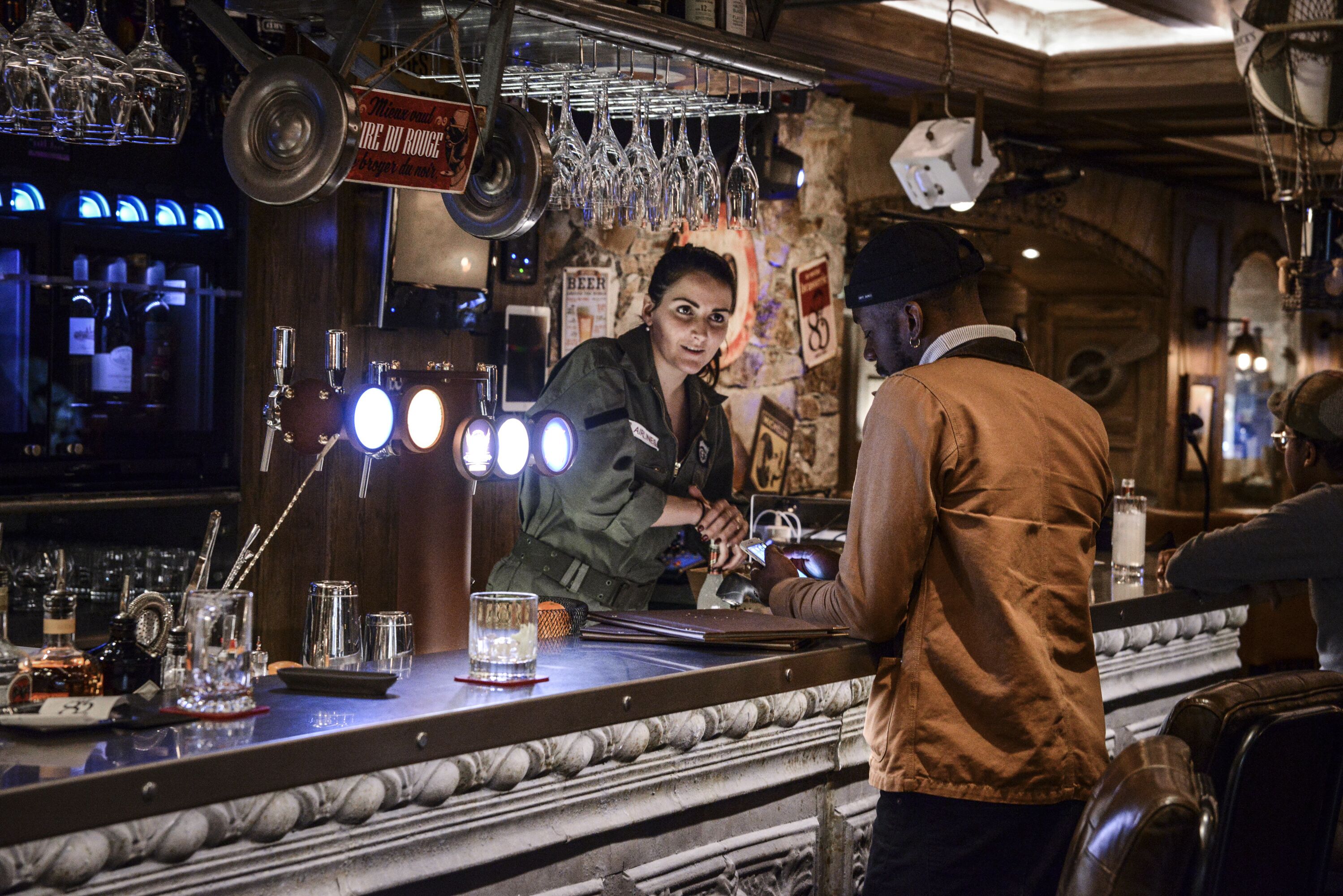 A bar with a marble countertop, glasses hanging above, and a sign indicating a beer price.