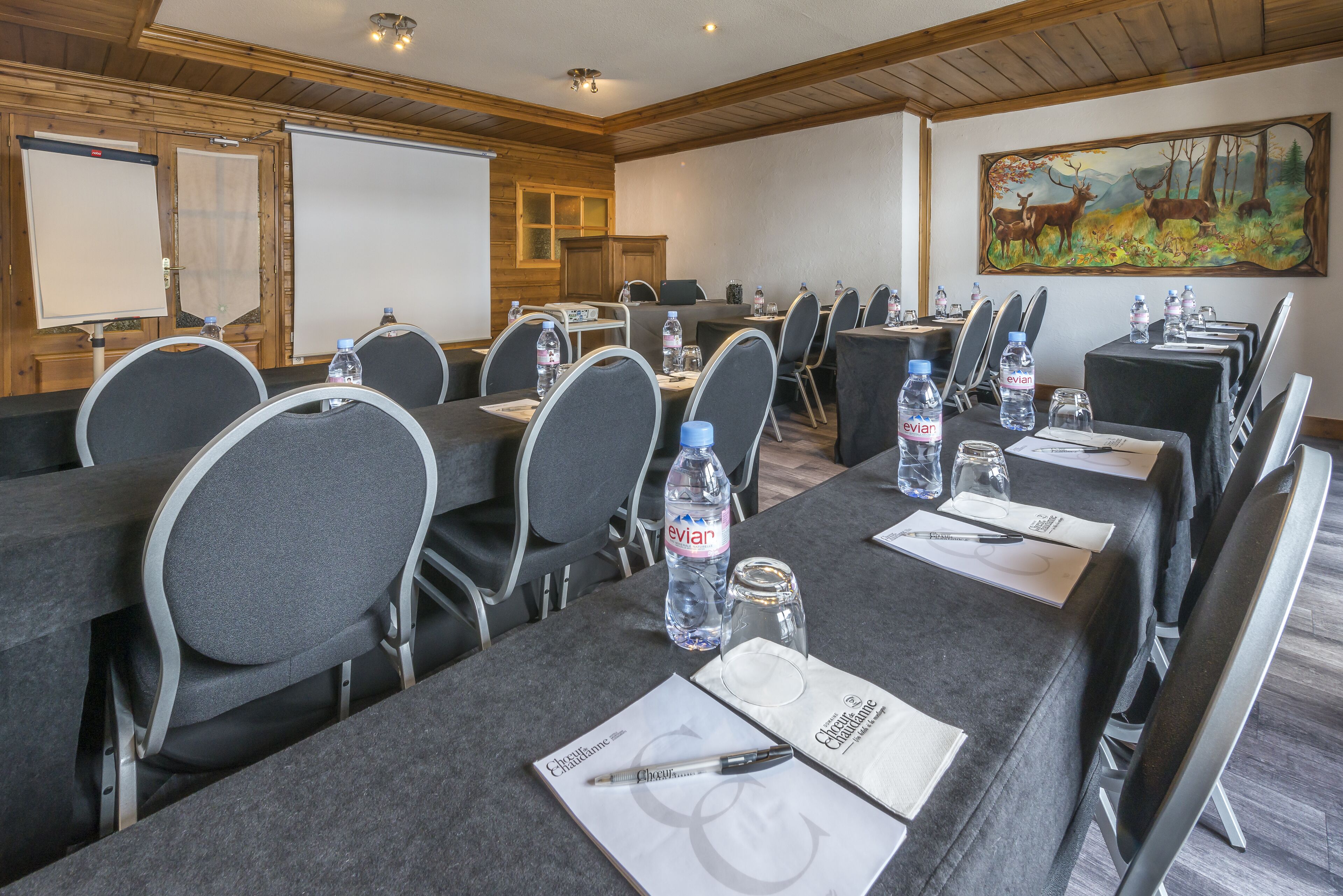 A conference room with multiple tables, chairs, and water bottles.