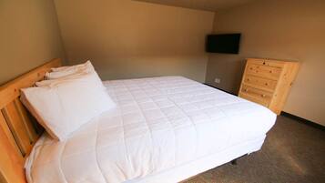 A neatly made bed with a wooden headboard and a wooden dresser with drawers.