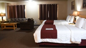 A hotel room with two beds, a sofa, a table, and curtains. - Woodside Dells Hotel & Suites (Wisconsin Dells)