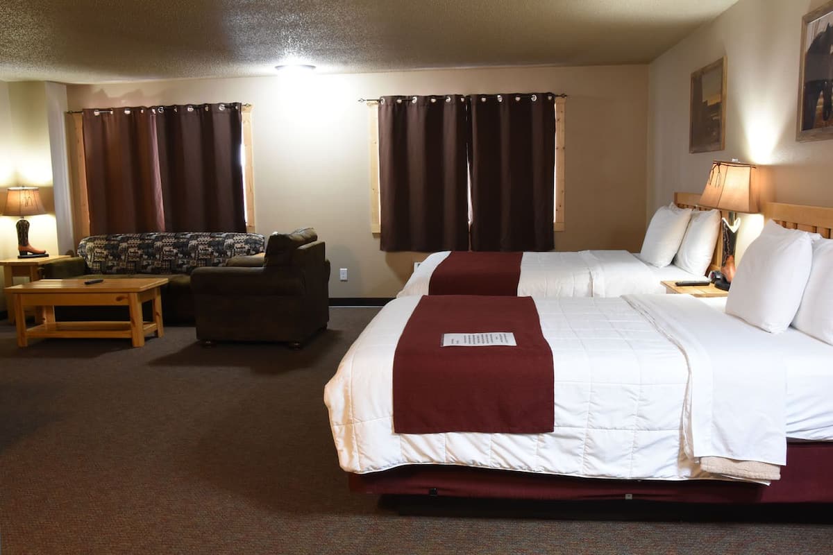 A hotel room with two beds, a sofa, a table, and curtains.
