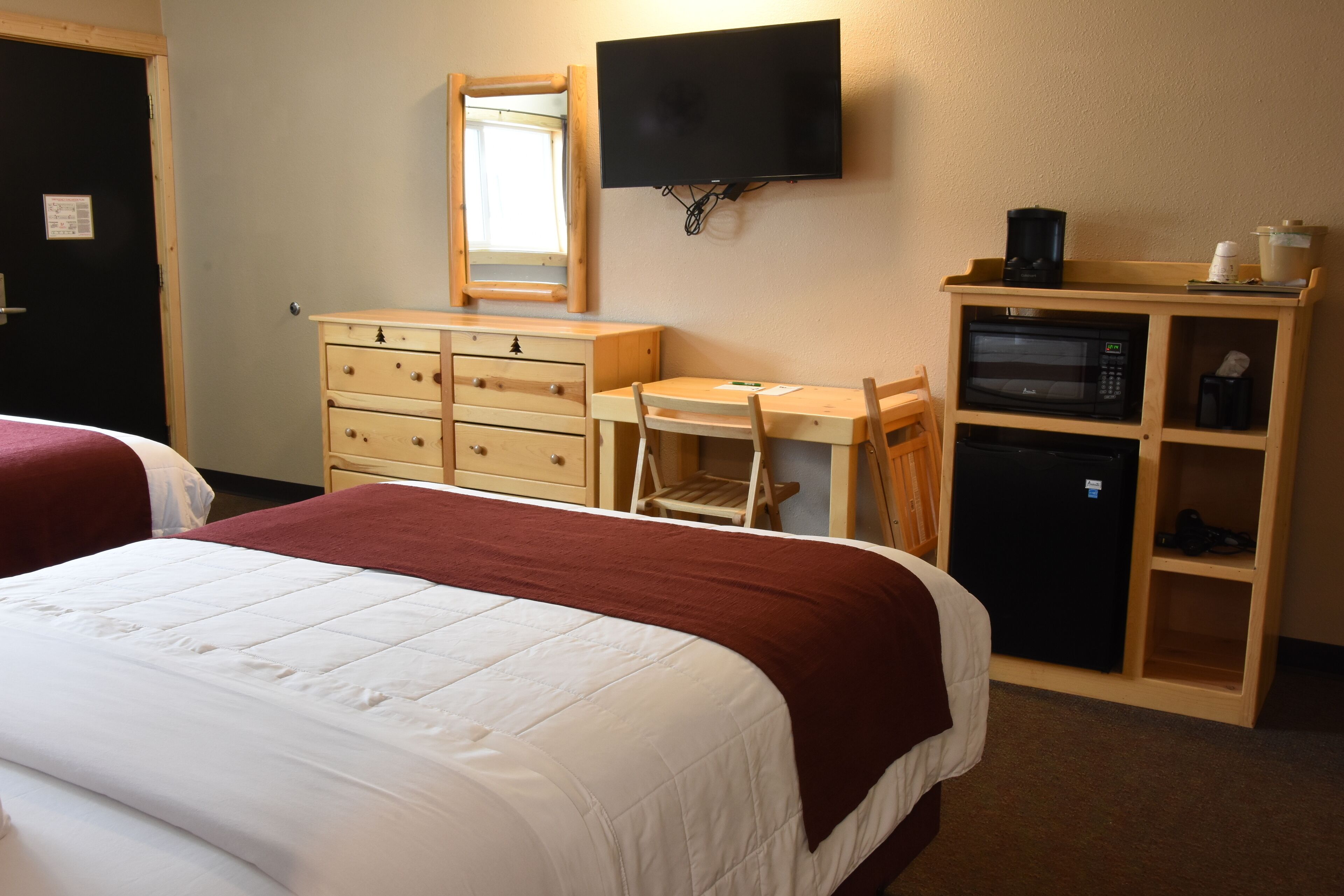 Een hotelkamer met twee bedden, een bureau, een stoel, een televisie, een magnetron en een koelkast.