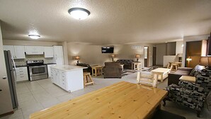 A compact living space with a kitchenette, a dining area, and a seating area with a TV. - Woodside Dells Hotel & Suites (Wisconsin Dells)