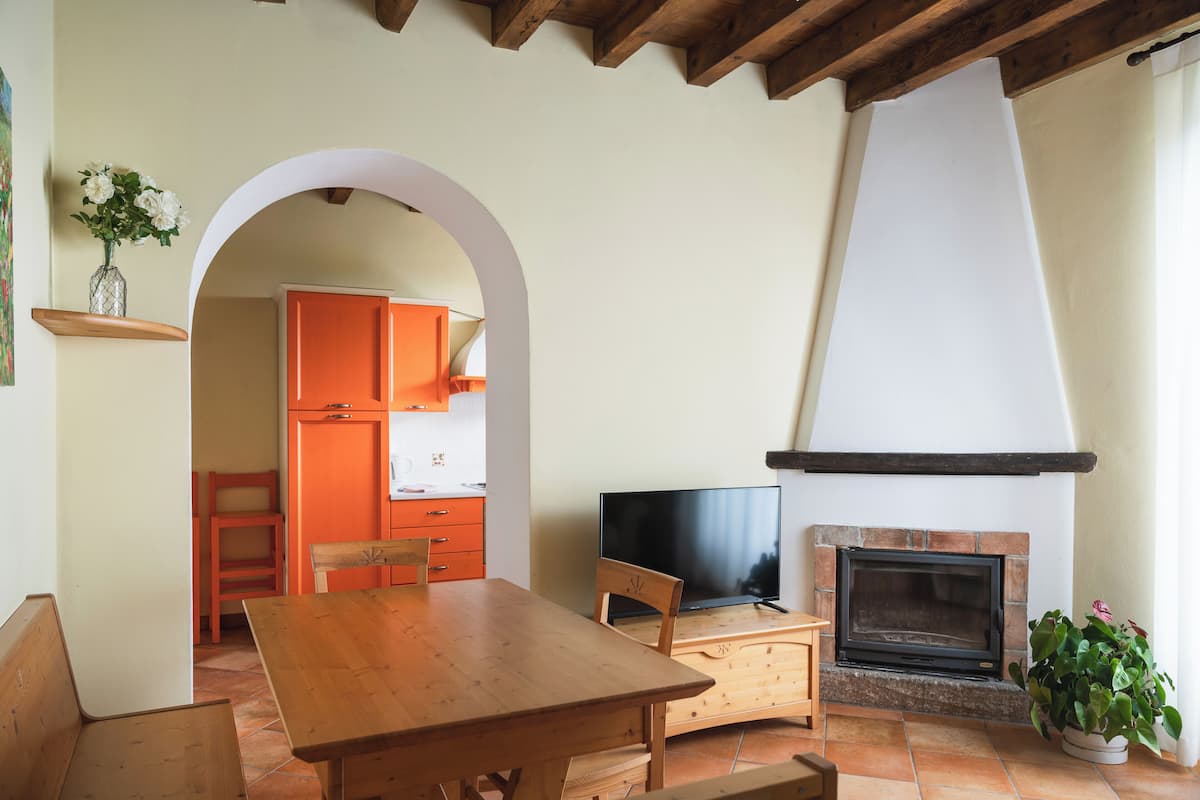 A cozy living room with a fireplace, wooden furniture, and an archway leading to a kitchen.