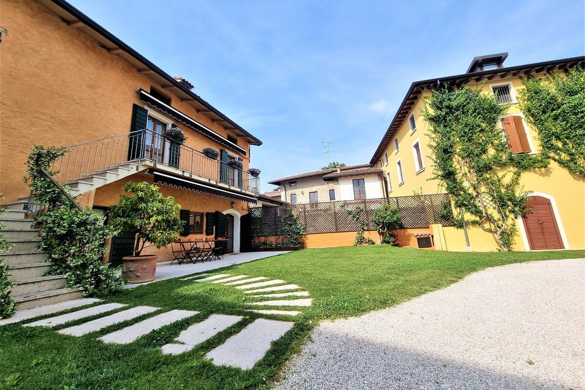 A courtyard with a paved walkway, a staircase, and a building with a balcony.