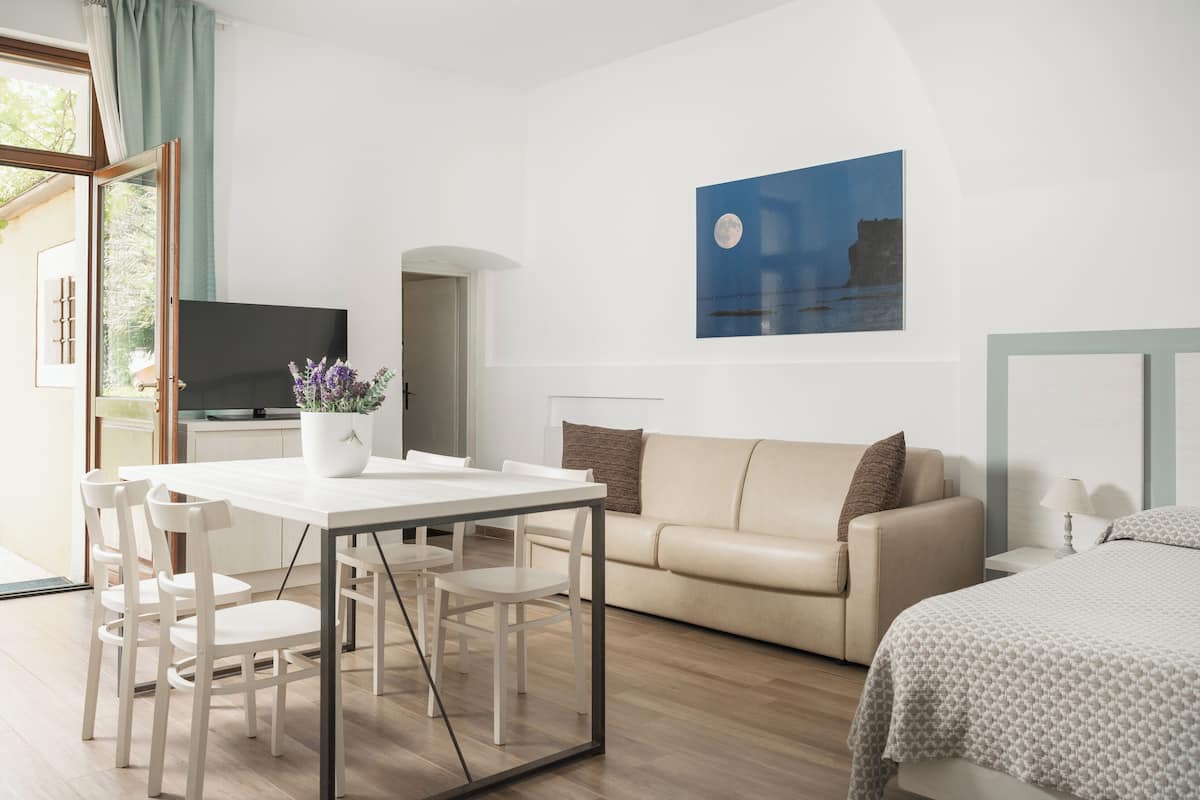 A modern, well-lit room with a dining area, a sofa, and a bed.