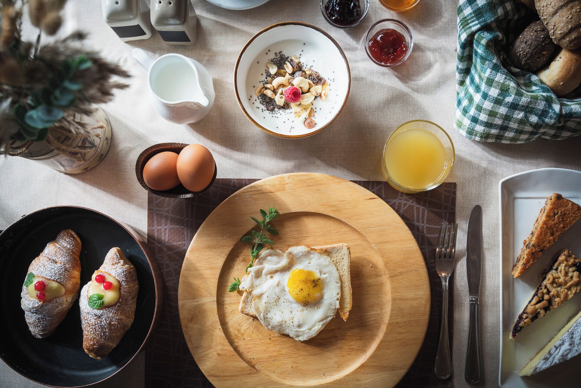 Una mesa con desayuno que incluye huevos, tostadas, pasteles y bebidas.