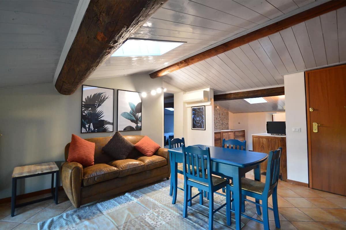 A cozy living room with a brown leather sofa, blue chairs, and a tiled floor.
