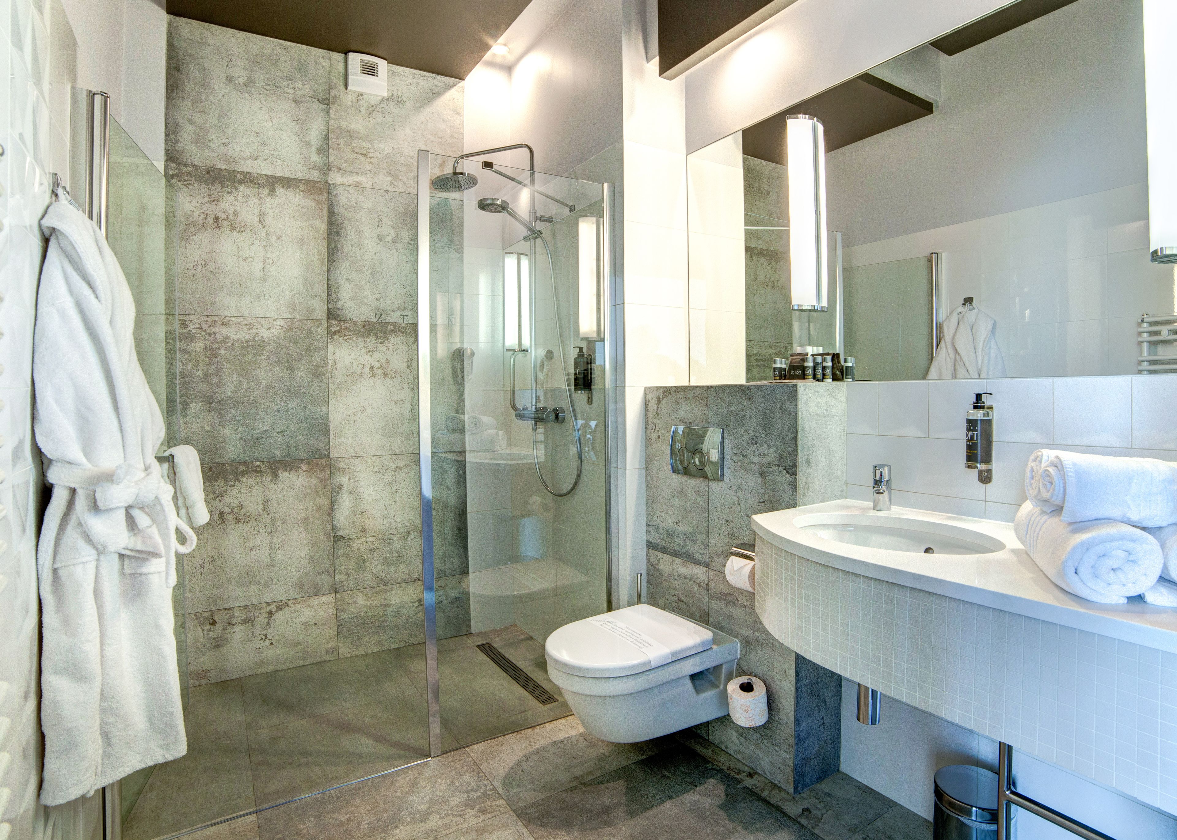 A modern bathroom with a glass-enclosed shower, a white sink, and a large mirror.