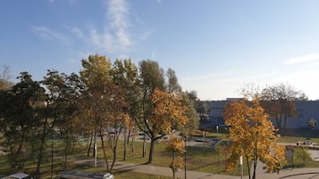 A parking area with a van, a car, and a bus. There are trees with autumn leaves and a building in the background.
