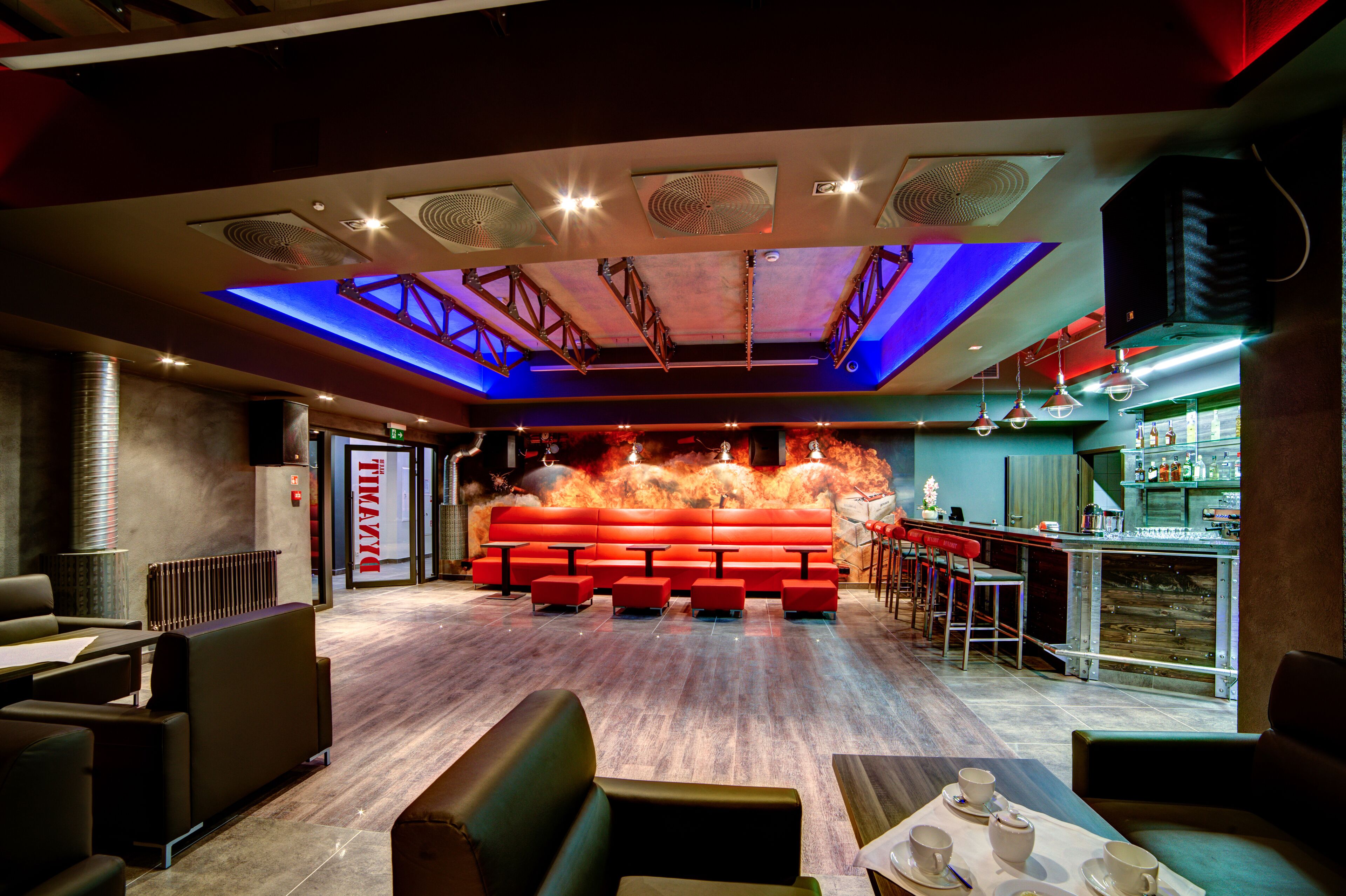 Eine moderne Bar mit Sitzgelegenheiten und einer Theke, gekennzeichnet durch ein einzigartiges Deckengestaltung und stimmungsvolle Beleuchtung.