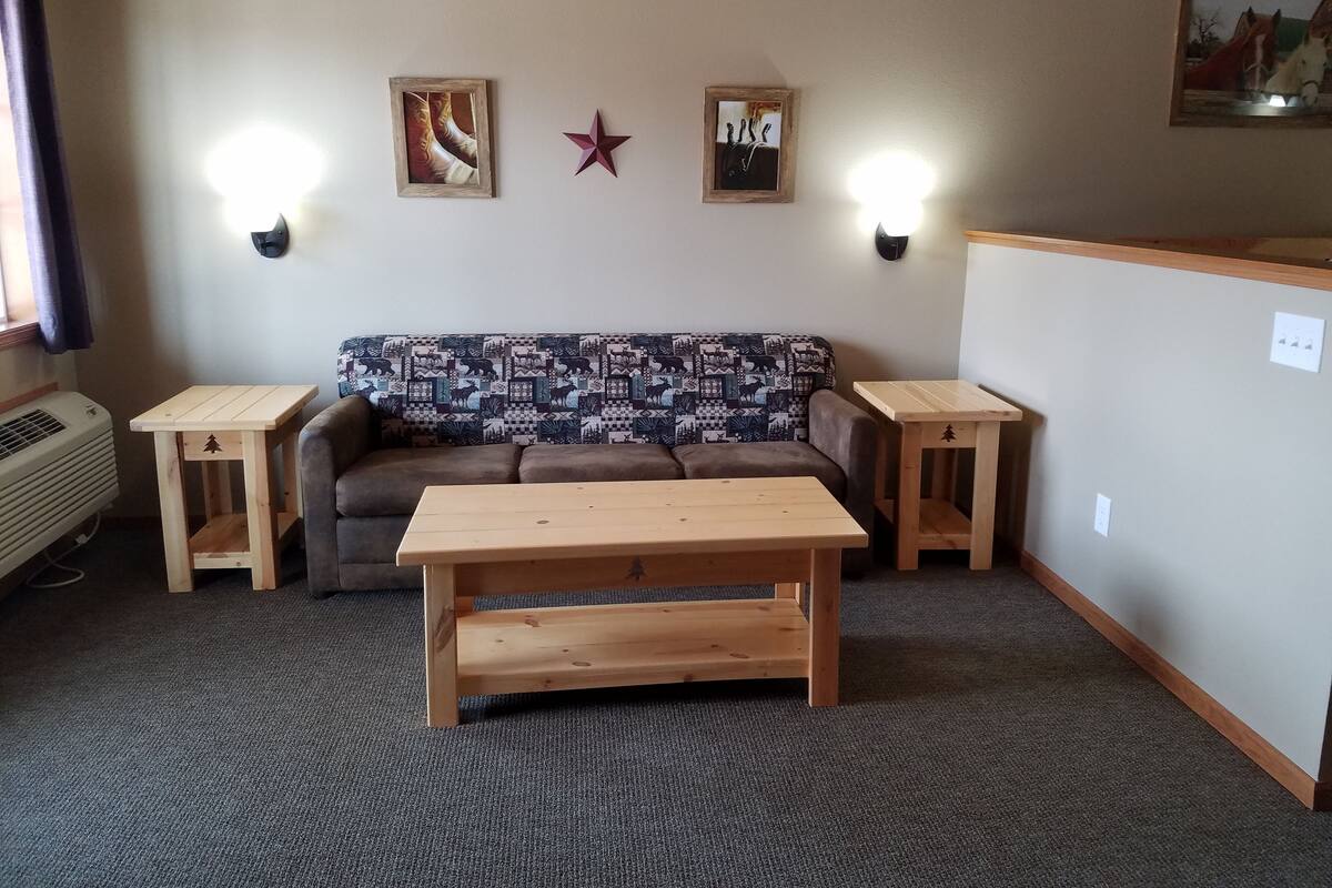 Uma sala de estar aconchegante com um sofá estampado, uma mesa de centro de madeira e duas mesas laterais.