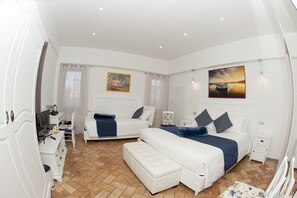 A modern bedroom with a large bed, a smaller bed, a desk, and a chair.