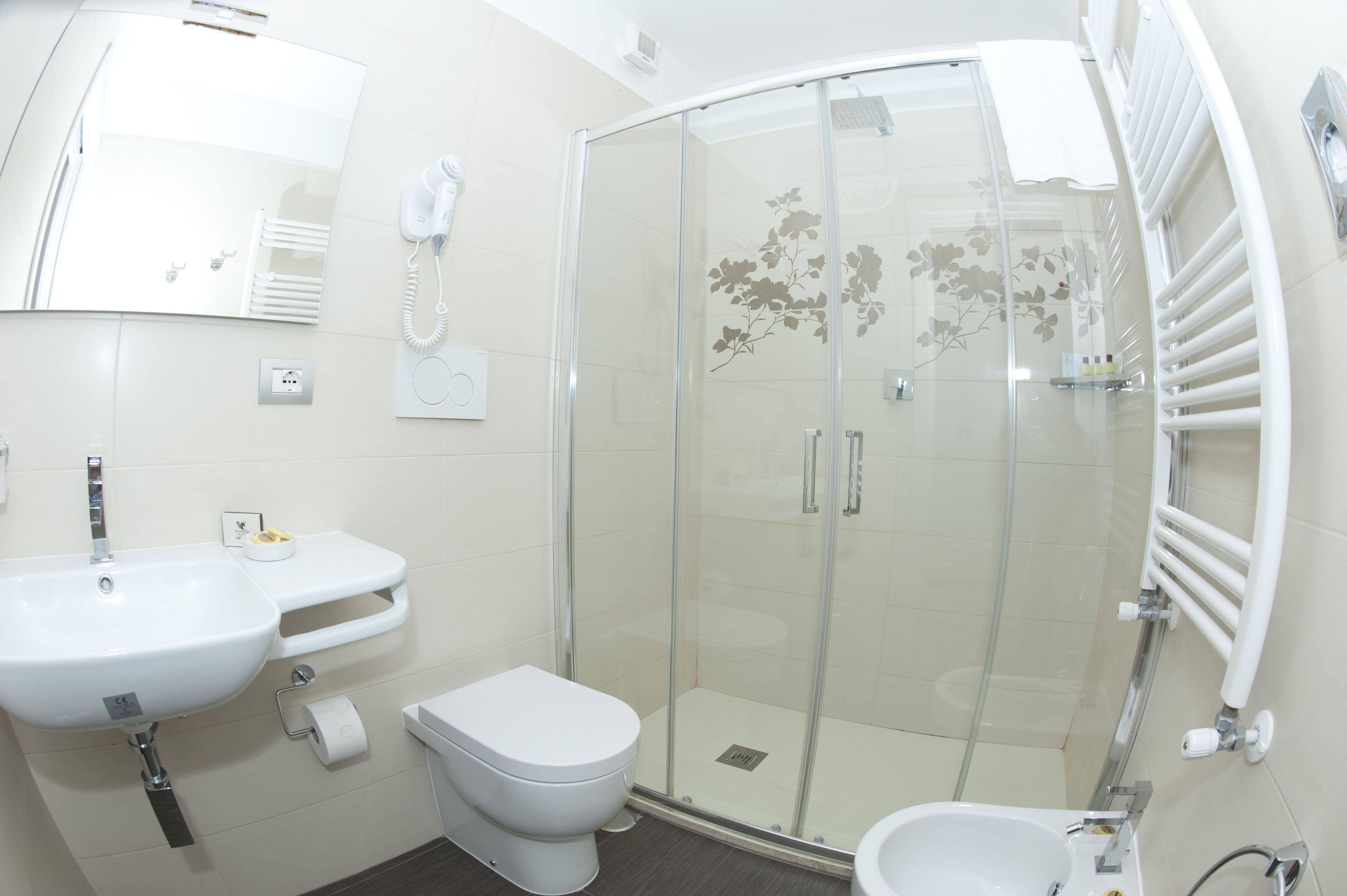 Un bagno moderno con box doccia in vetro, lavabo, WC e bidet.