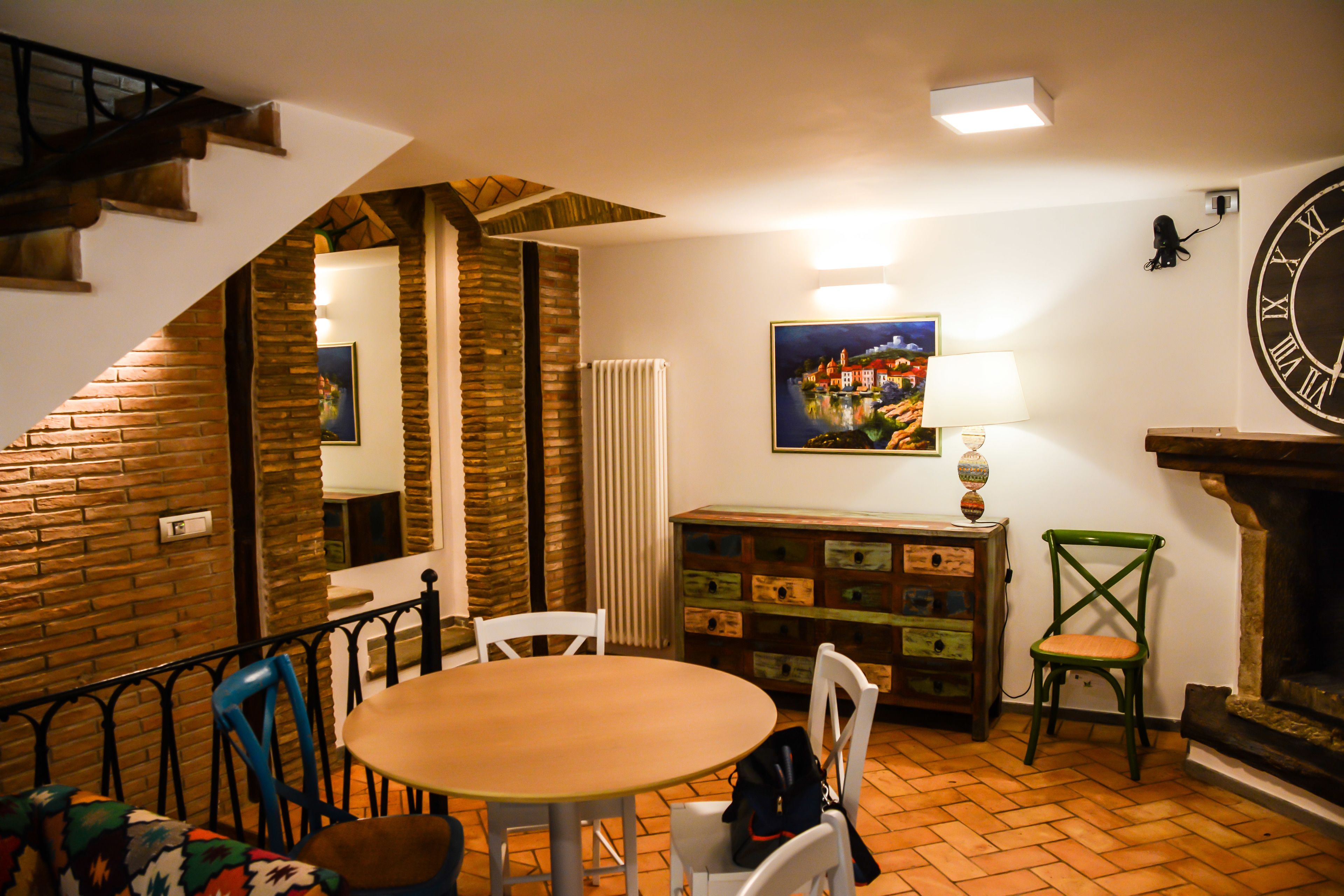 Un comedor acogedor con una mesa redonda, sillas, una chimenea y un reloj en la pared.