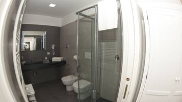 Un baño moderno con cabina de ducha de vidrio, inodoro y bidé.