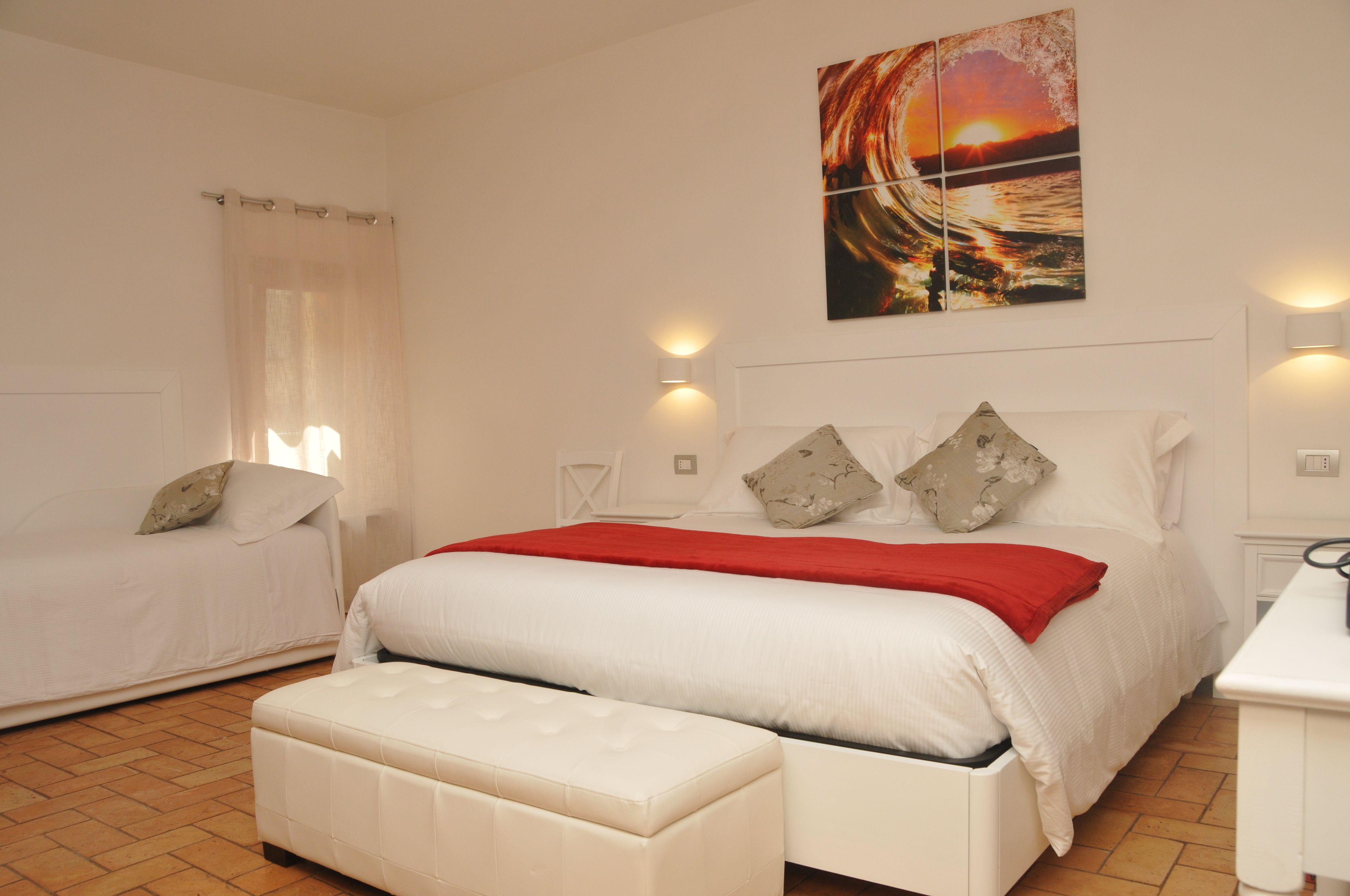 A bedroom with a bed, a bench, a nightstand, and a wall-mounted painting.