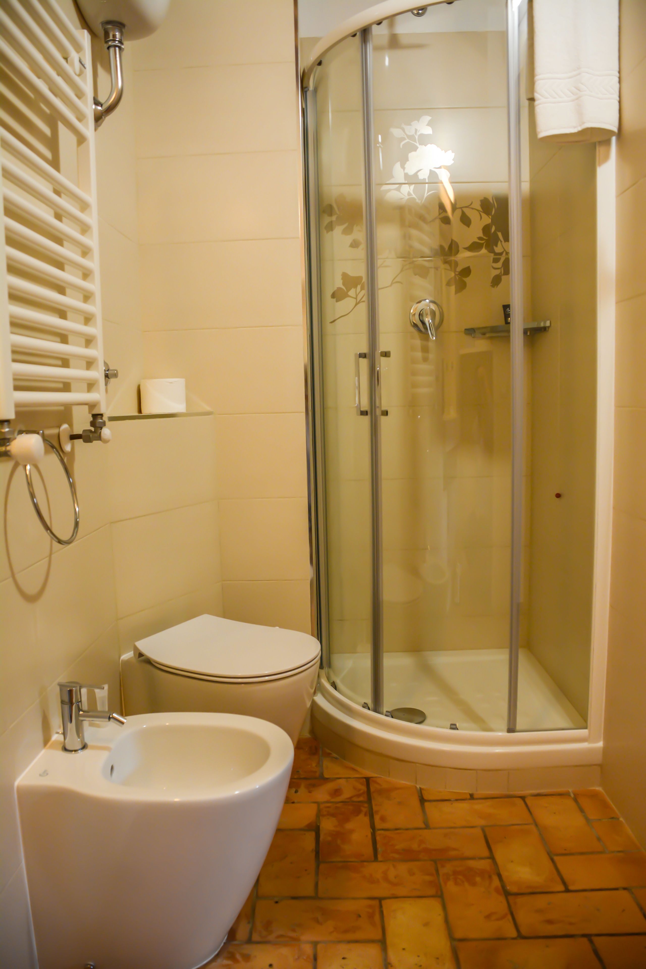 A bathroom with a glass-enclosed shower, a toilet, and a bidet.
