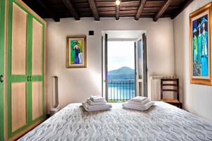 Un dormitorio con una cama, un armario verde, un cuadro y vistas al mar.