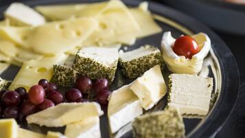 Una tabla de quesos con varias variedades de queso, uvas y un tomate cherry.