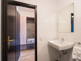 Un baño moderno con un lavabo blanco, una toalla colgada en la pared y suelo de madera.