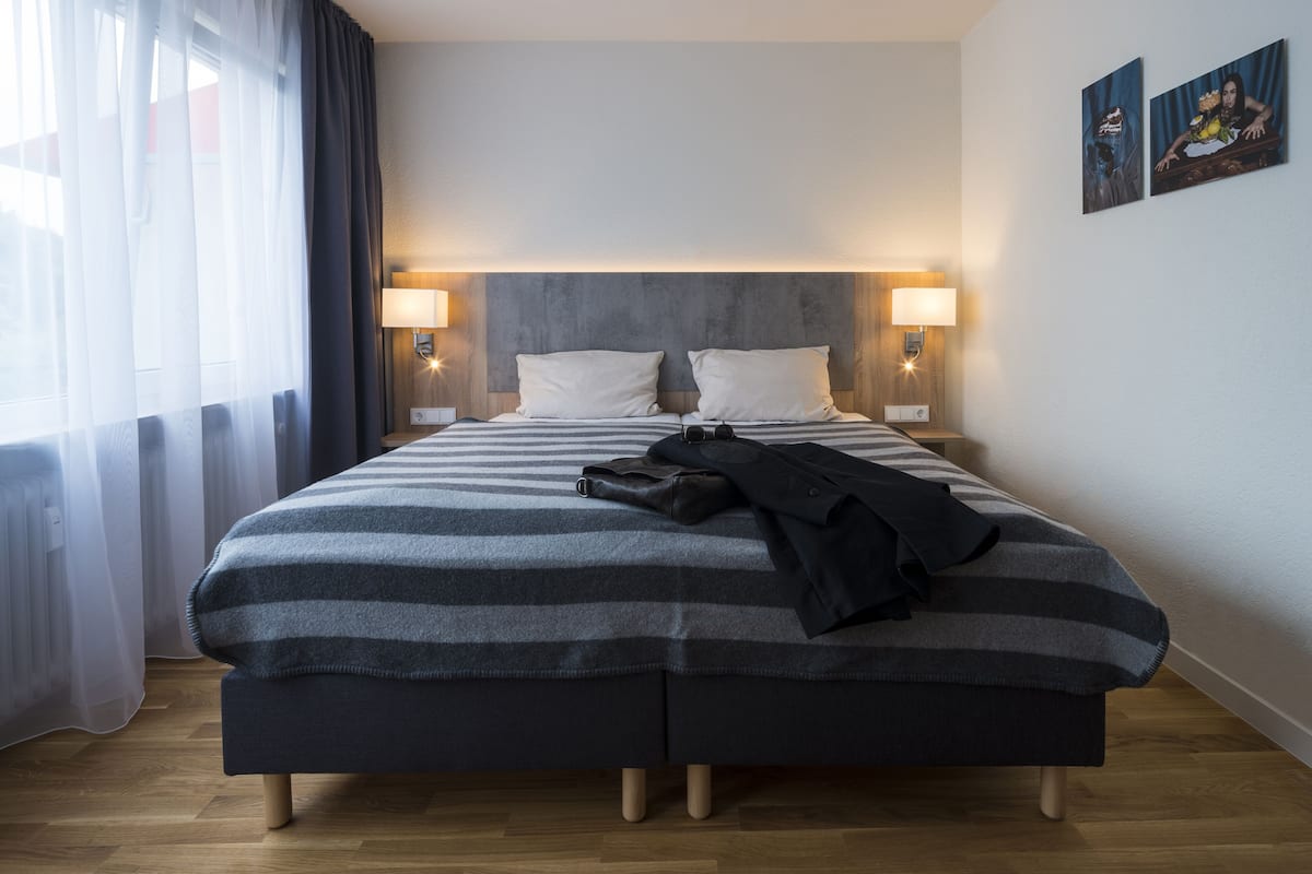 Ein Doppelbett mit einer gestreiften Decke, zwei Nachttischlampen und ein Paar Schuhe auf dem Bett.