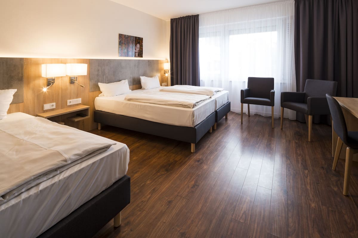 Ein Hotelzimmer mit zwei Betten, einem Schreibtisch und einem Stuhl.