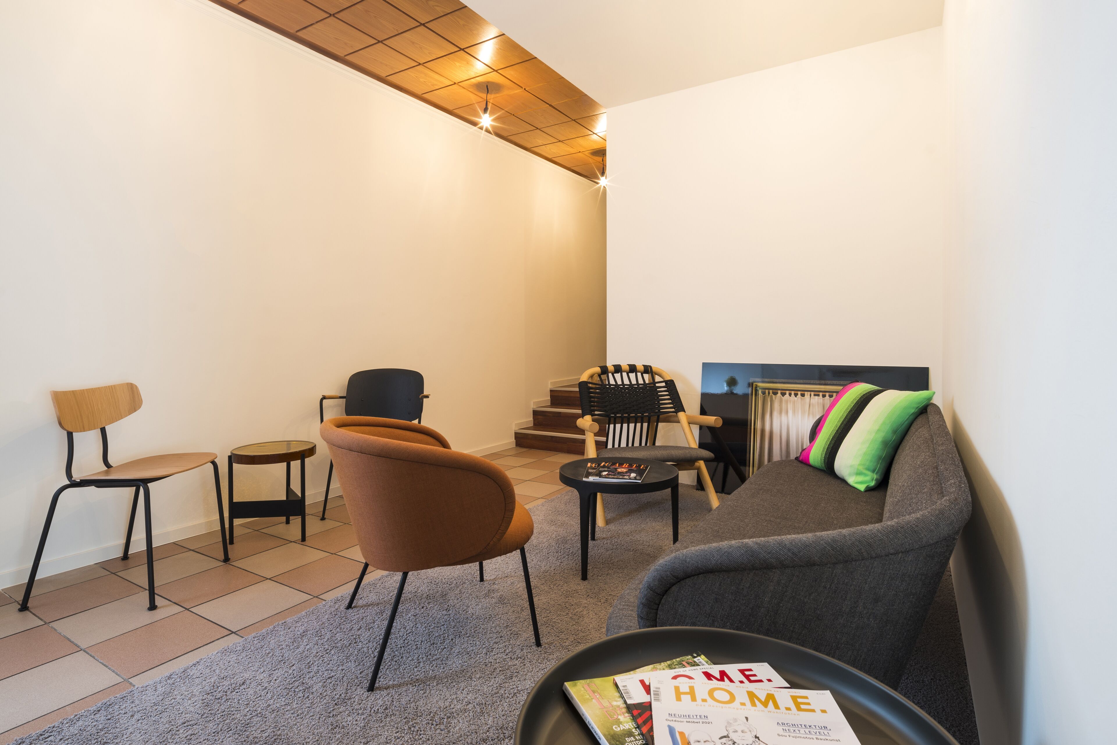 Een moderne woonkamer met een bank, fauteuils, een salontafel en een tijdschrift op de tafel.