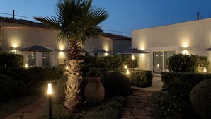 A well-lit outdoor area with stone pathways, neatly trimmed bushes, and a palm tree. - Tonnara di Sciacca (Sciacca)
