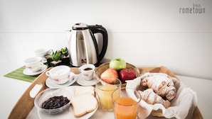 Un plateau de petit-déjeuner avec des croissants, des pommes, du jus et des tasses de thé.