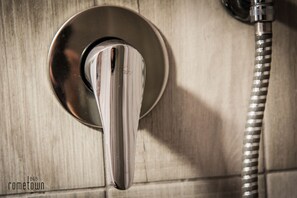 Un soffione cromato fissato a parete con un tubo flessibile.