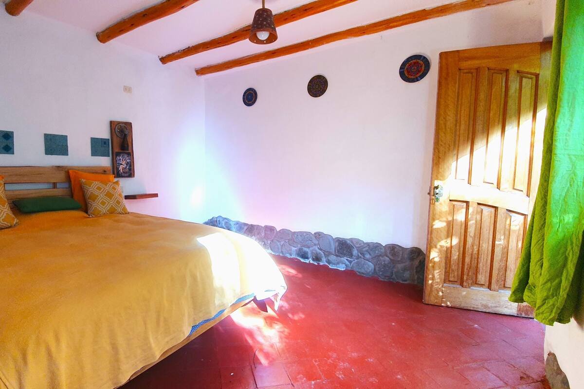 A bedroom with a wooden bed, a stone wall, and a wooden door.