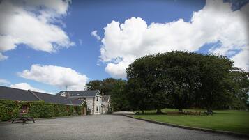 A large house with a gravel driveway and a grassy lawn.