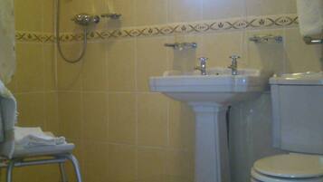 A bathroom with a shower, sink, toilet, and a small window.