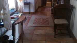 A cozy living room with a fireplace, a dining area with a table and chairs, and a hallway leading to another room. - Coolanowle Country House (Arless)
