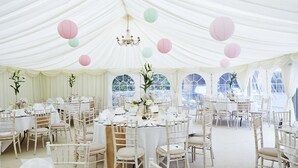 A tented event space with round tables and white chairs, decorated with paper lanterns and floral arrangements. - Coolanowle Country House (Arless)