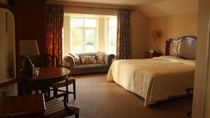 A bedroom with a bed, a sofa, a dining table, and a lamp. - Coolanowle Country House (Arless)