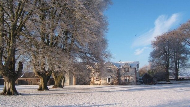 A stone building with multiple windows and a snow-covered ground. - Coolanowle Country House (Arless)