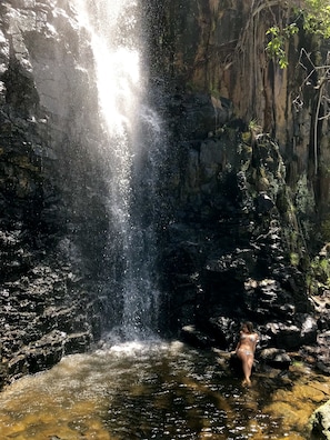 A waterfall in a rocky, natural setting with clear water. - Pousada do Vale (Fernando de Noronha)