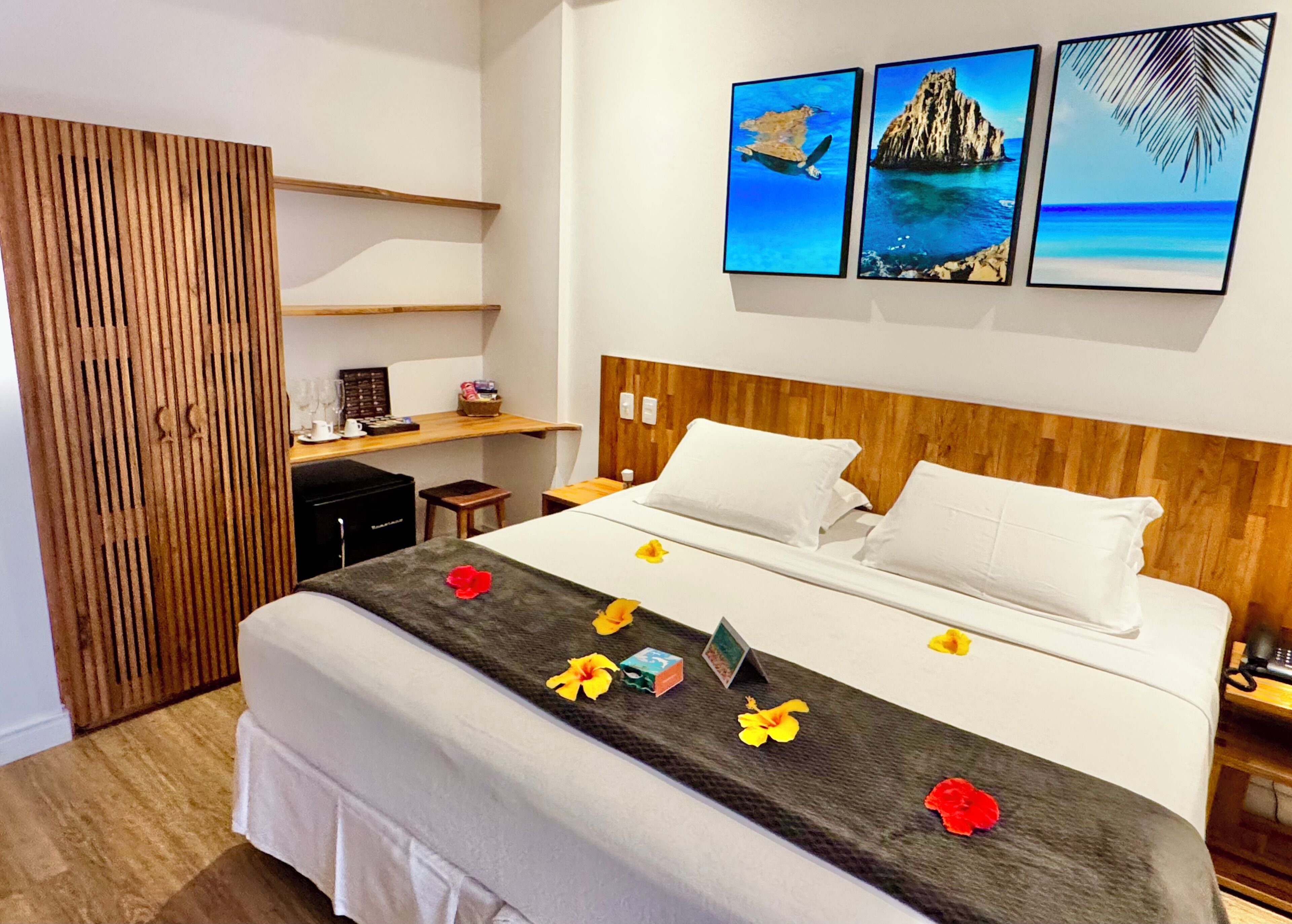 Habitación de hotel con cama, cabecero de madera, escritorio y silla, y una obra de arte en la pared.
