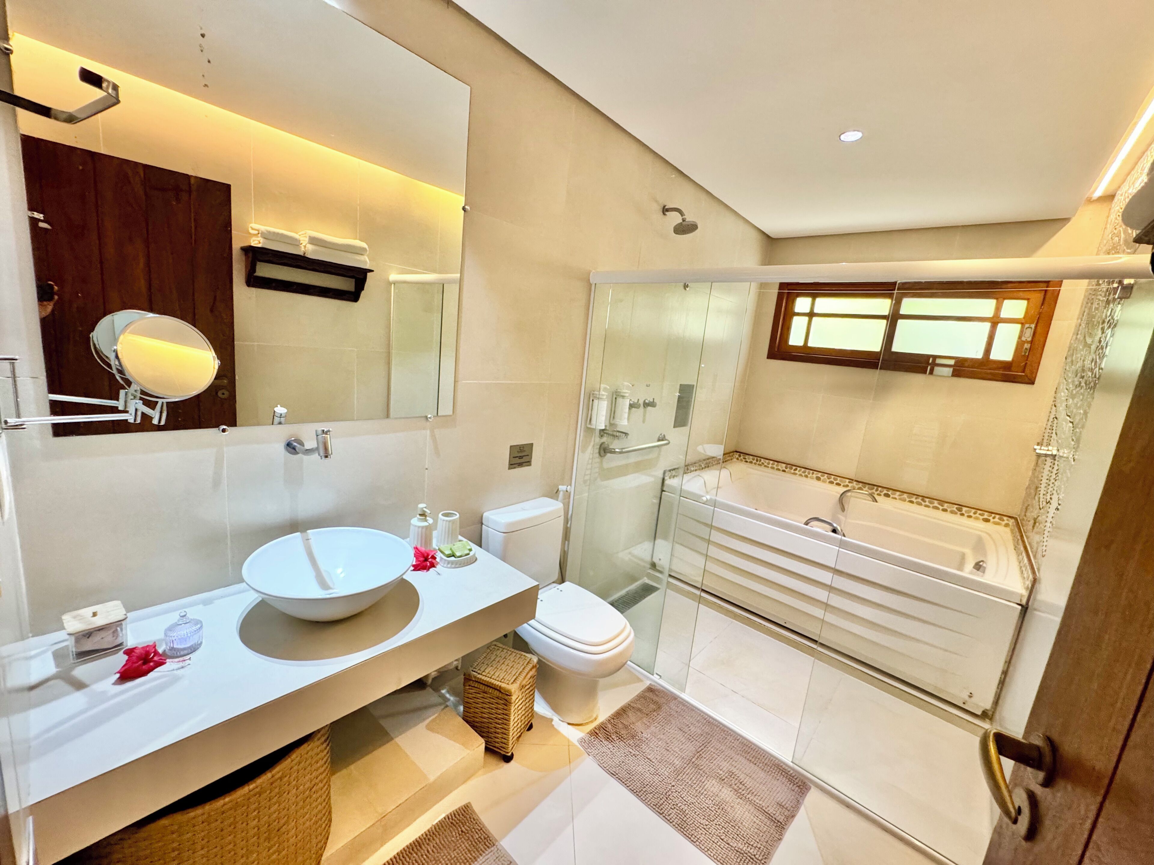 A modern bathroom with a large mirror, white sink, and glass-enclosed shower.