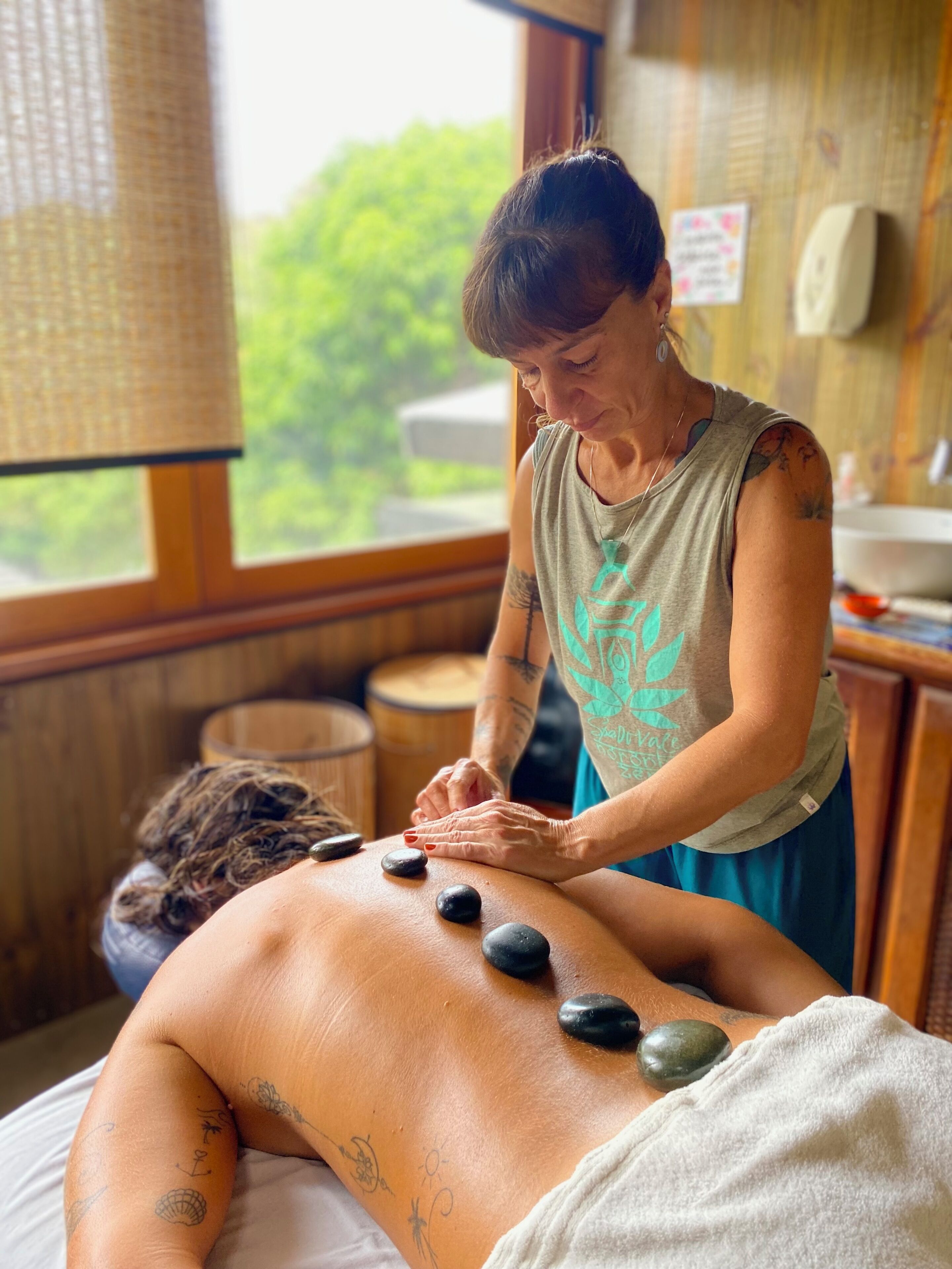 A massage therapy session with a person lying on a massage table, receiving a back massage with stones.