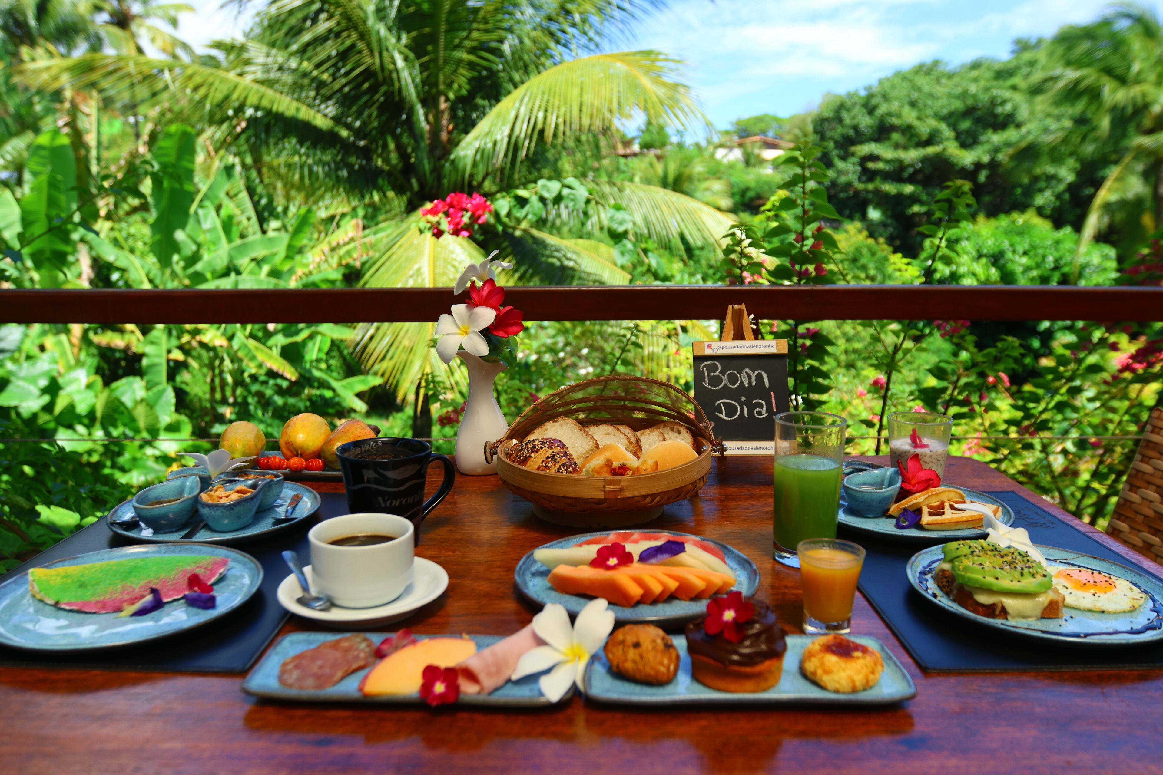 Una mesa de desayuno con diversos alimentos y un letrero que dice 'Bom dia'.