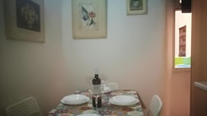 Un coin repas avec une table dressée pour quatre personnes, des chaises et une bouteille de vin.