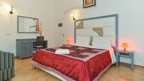 Une chambre à coucher avec un grand lit, un bureau et une chaise. Il y a deux tables de chevet avec des lampes.