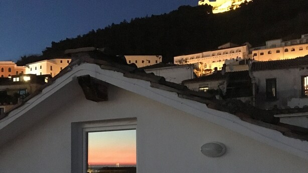 A building with a sloped roof, a door leading to an interior space, and a table with chairs outside. - Casa Maria (Salerno)